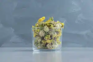 Glass of dry chrysanthemum flowers on stone background