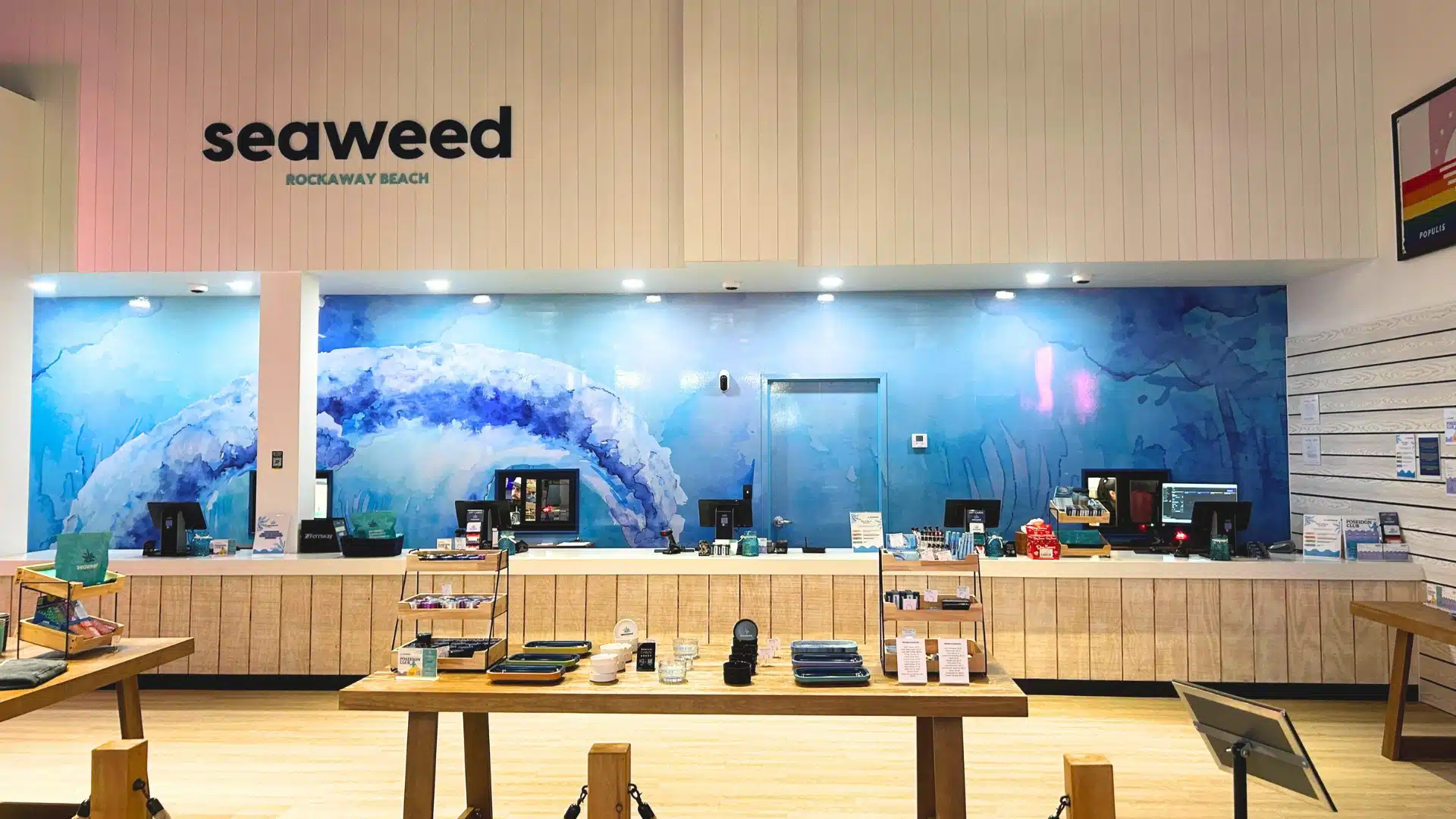 Interior of Seaweed, a licensed dispensary in Rockaway Beach, showing the counter and wave mural